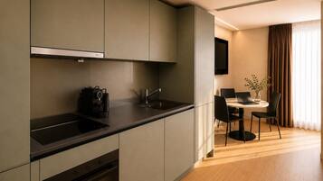 A modern kitchen with built-in appliances, a dining area with a table and chairs, and a flat-screen TV mounted on the wall.