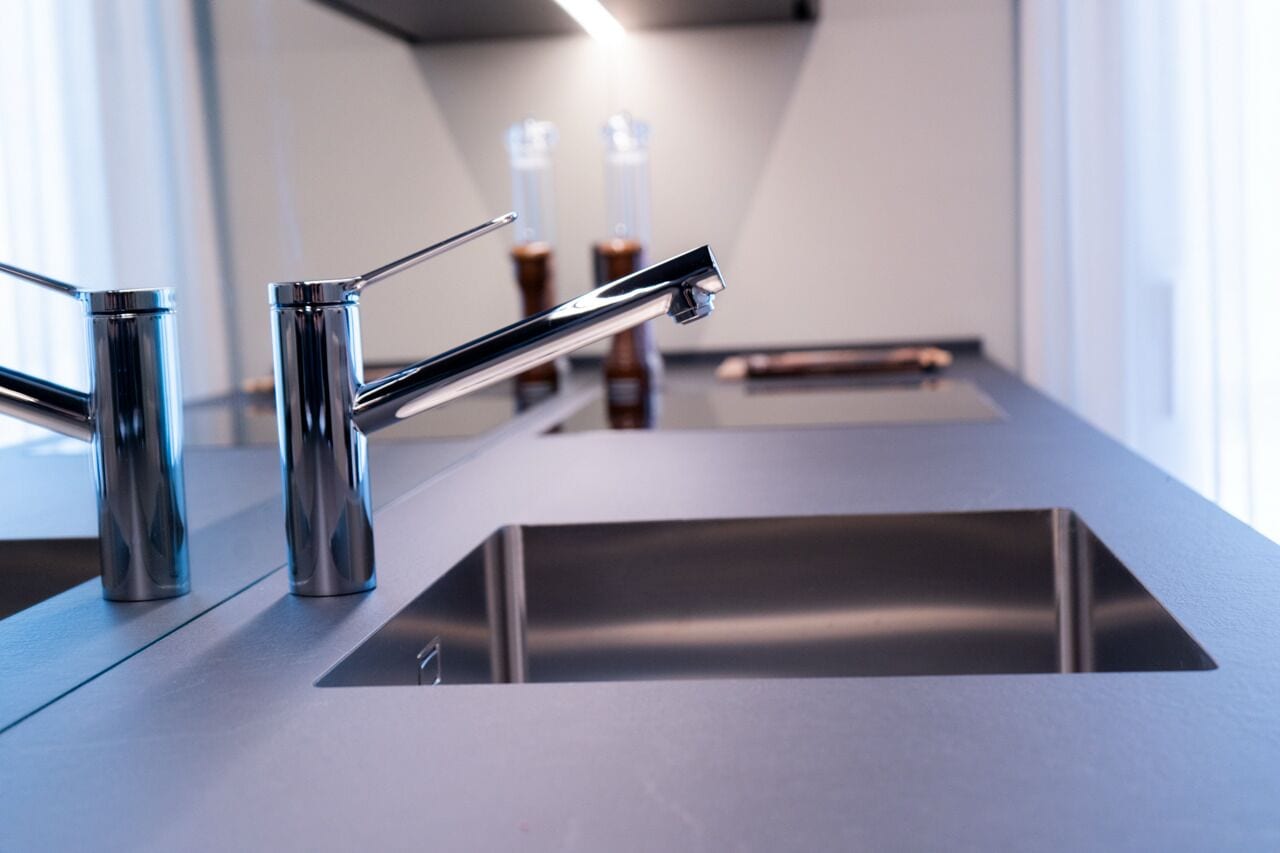 Une cuisine moderne dotée d’un évier en acier inoxydable et de deux robinets.