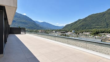 Una terraza en la azotea con vistas a un río y montañas.