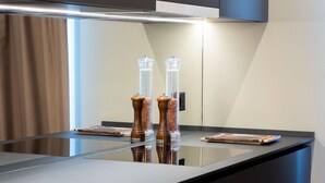 A modern kitchen with a sleek black countertop, a built-in stove, and a stainless steel range hood. - Arbed Living Hotel (Arbedo-Castione)