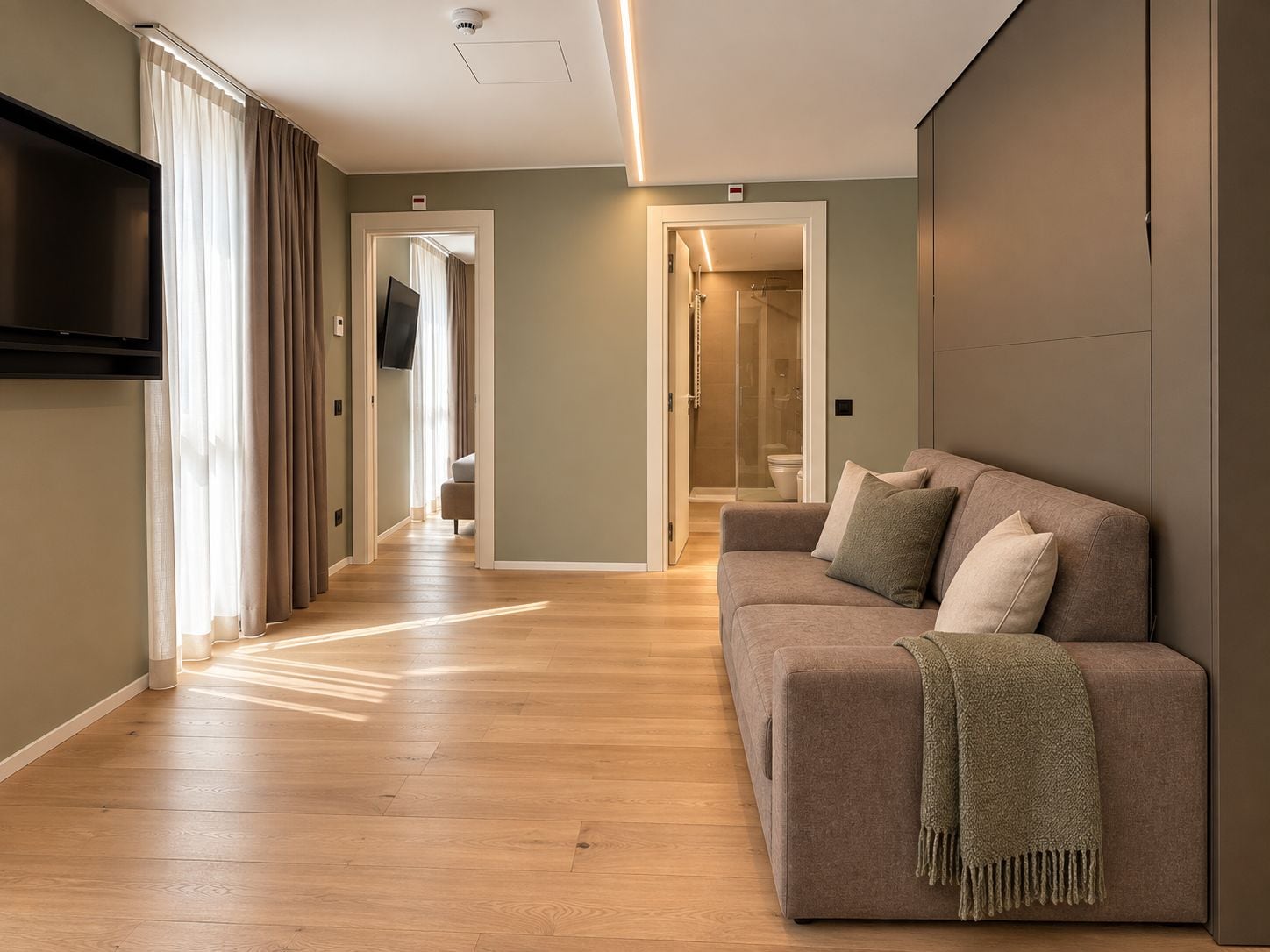 Una sala moderna con un sofá, una televisión y un pasillo que conduce a un baño.
