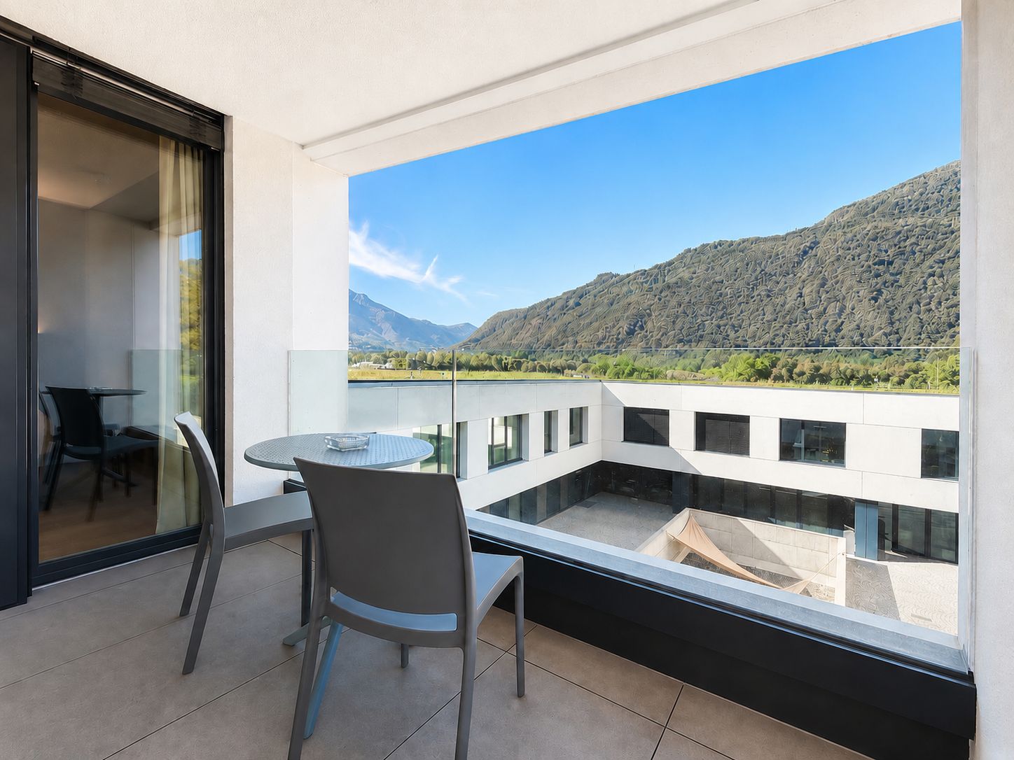 Un balcone con tavolo e sedie, vista su un paesaggio montuoso.
