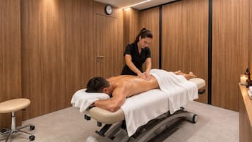 Une salle de massage équipée d’une table de massage, où un massothérapeute prodigue un massage du dos à un client.