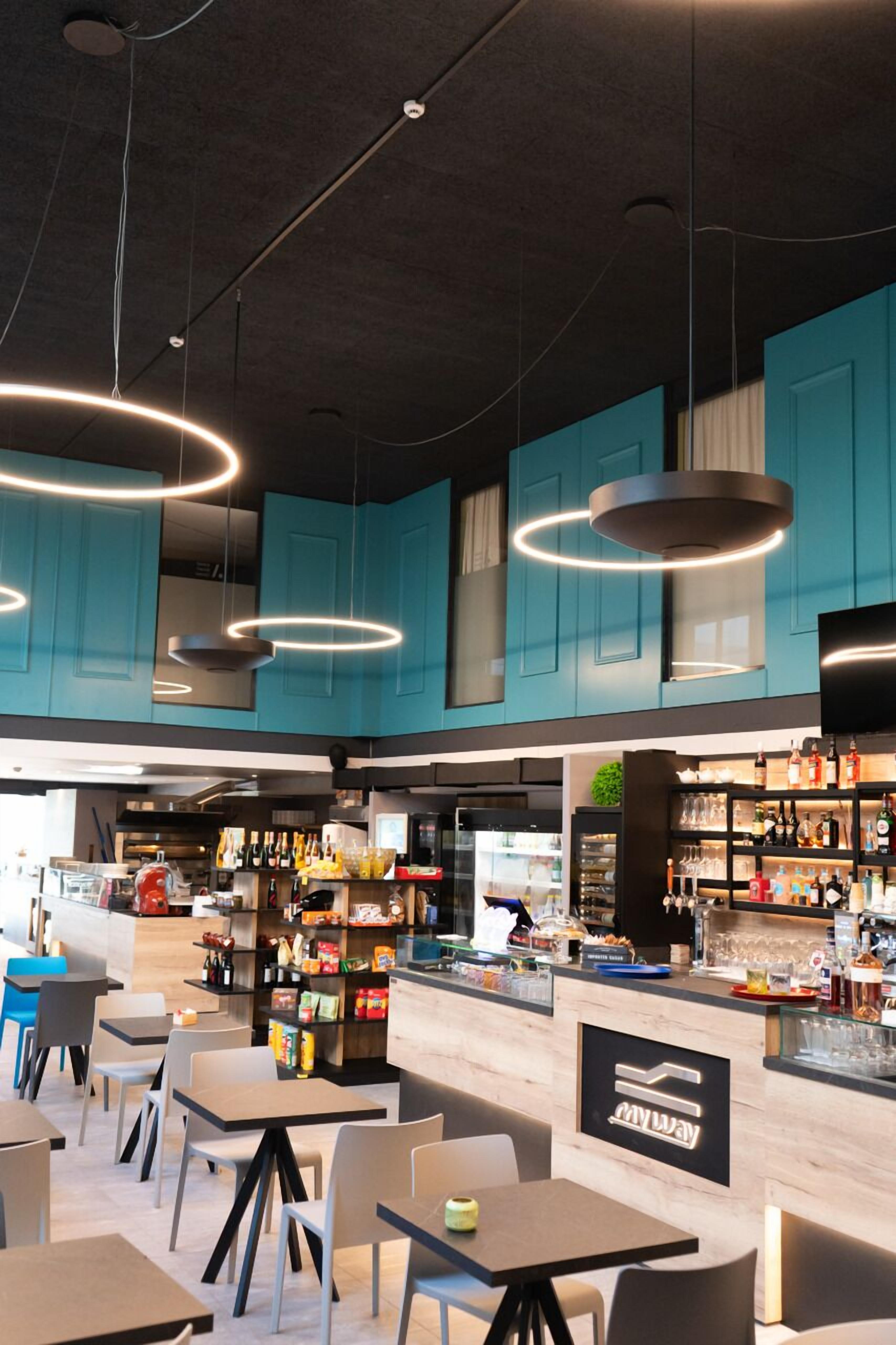 Un restaurant moderne aux murs de couleur turquoise, doté d’un bar et d’un espace aménagé pour s’asseoir.
