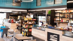 A modern restaurant with teal walls, a bar area, and seating arrangements. - Arbed Living Hotel (Arbedo-Castione)