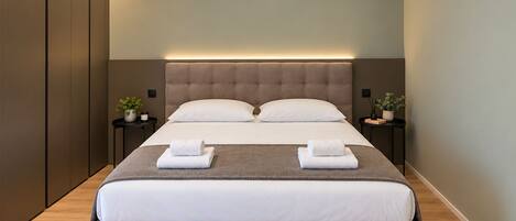 Une chambre à coucher moderne avec un grand lit, deux tables de chevet et une armoire intégrée.