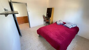 Un dormitorio con cama, una silla y un escritorio.
