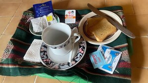Bandeja de desayuno con una taza, tostadas, sobre de café instantáneo y un sobrecito de té.