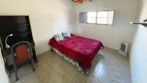 Un dormitorio con cama, una silla, una ventana y un ventilador de techo.