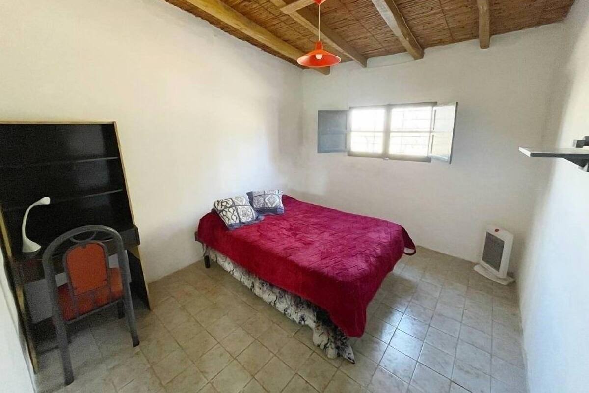 A bedroom with a bed, a chair, a window, and a ceiling fan.