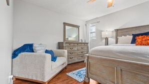 Une chambre à coucher comprenant un lit, une commode, une chaise et une table de chevet.