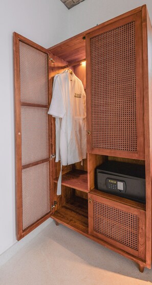 A wooden wardrobe with a hanging rack, a shelf with a black electronic device, and a mesh door. - 22land Residence Suite (Hanoi)
