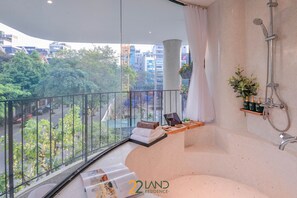Ein modernes Badezimmer mit Badewanne, Dusche und einem Balkon mit Blick auf die Stadt.