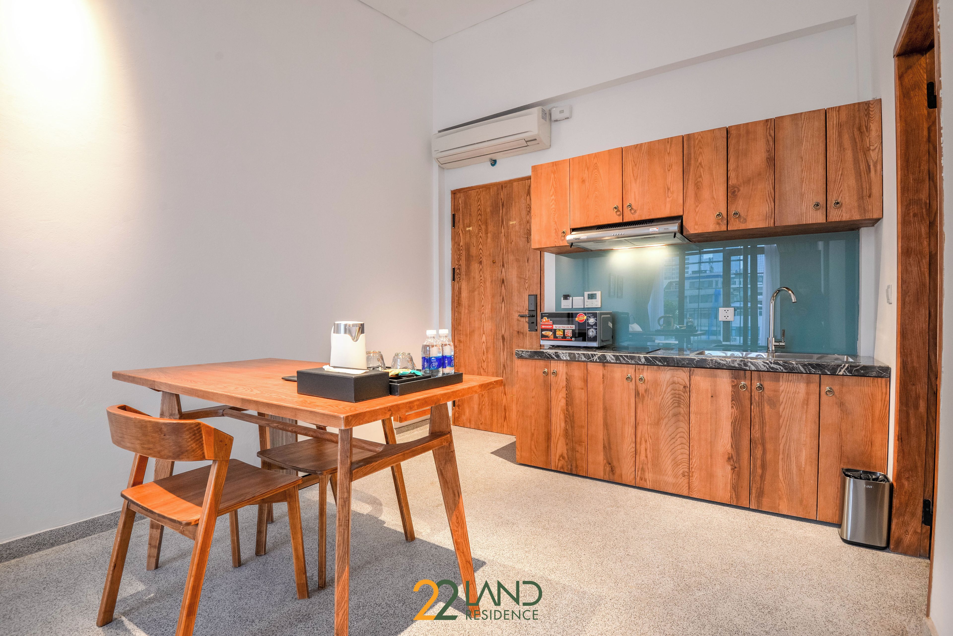 A compact kitchen with wooden cabinets, a countertop, and a sink. There is a table with chairs and a coffee maker.