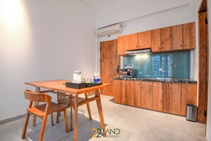 Eine kleine Küche mit Holdekor, einer Arbeitsplatte und einem Spülbecken. Es gibt einen Tisch mit Stühlen und eine Kaffeemaschine.