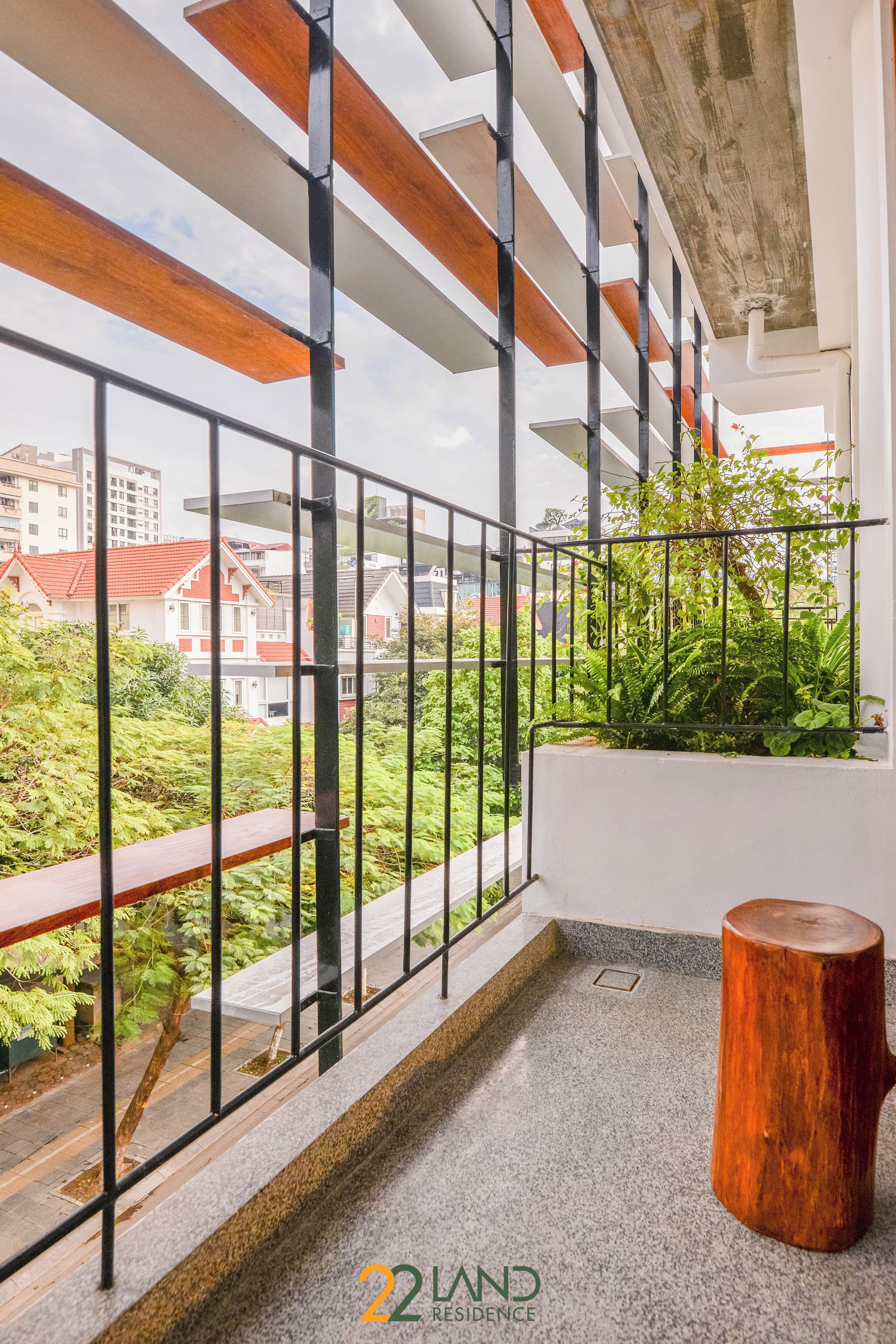A balcony with a metal railing, a wooden bench, and a potted plant.