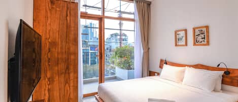 Habitación de hotel con una cama grande, televisión y vista a la ciudad a través de un ventanal.