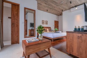 A bedroom with a wooden bed, a bedside table with a magazine, a mirror, and a small plant. - 22land Residence Suite (Hanoi)