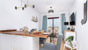 Une cuisine moderne avec un plan de travail en bois, des armoires blanches et un coin repas comprenant une chaise grise et une petite table.