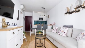 Un salon moderne avec un canapé, une table basse et un coin repas comprenant des chaises, et une cuisine en arrière-plan.