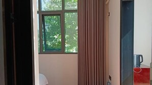 A room with a window, a curtain, a bed, and a coffee machine. - Yinjiang Lihao Hotel (Yinjiang)