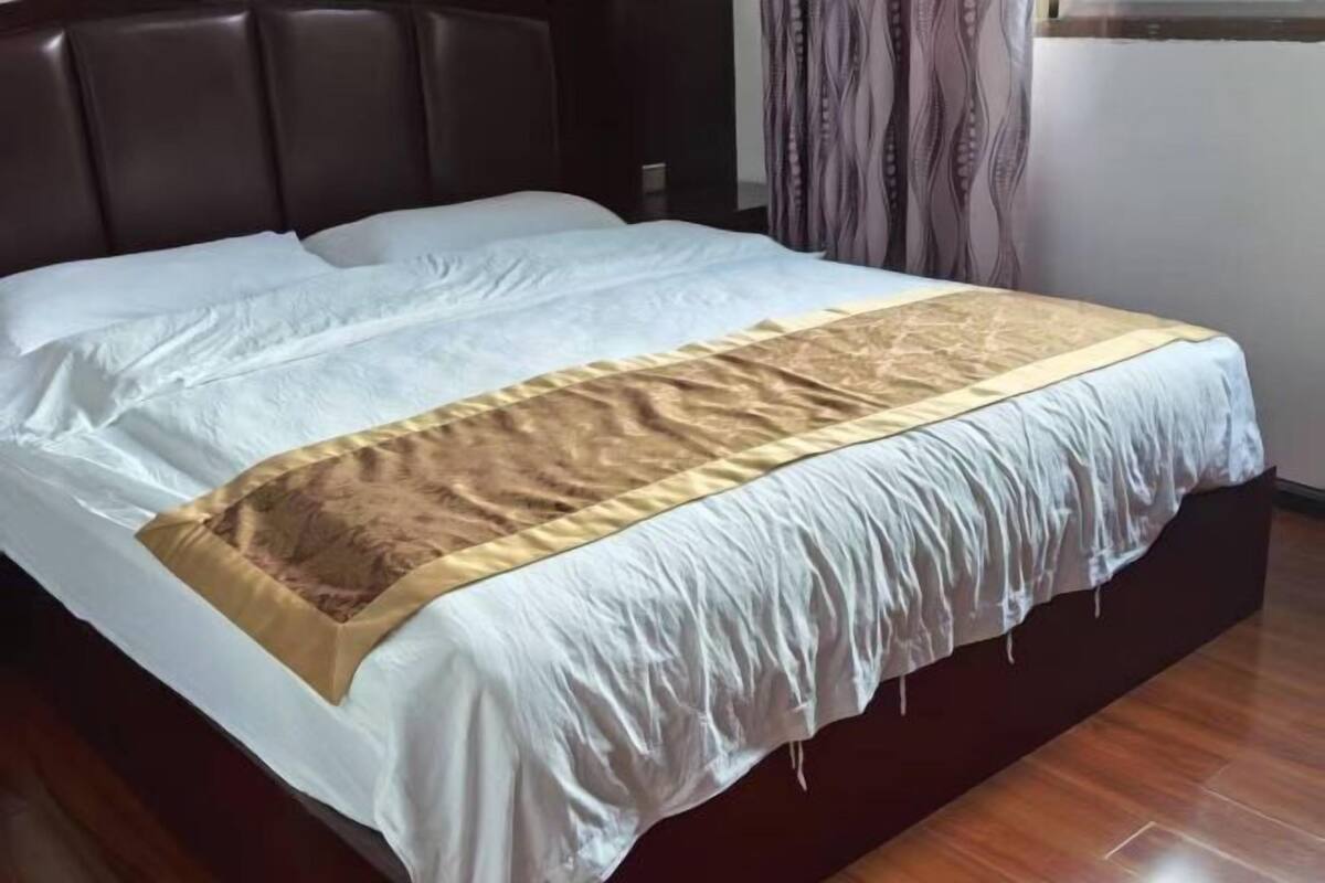 A bed with a headboard, a white bedspread, and a brown accent.