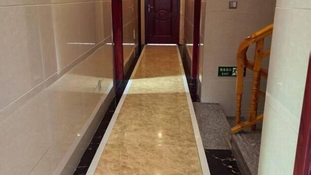 A hallway with a marble floor, a wooden door at the end, and a bamboo railing on the right. - Yinjiang Lihao Hotel (Yinjiang)