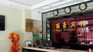 A hotel reception area with a reception desk, a clock, and a sign for the Regal Riverside Hotel. - Yinjiang Lihao Hotel (Yinjiang)