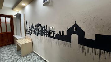 Un pasillo con una pared texturizada que presenta una silueta negra de un horizonte urbano.
