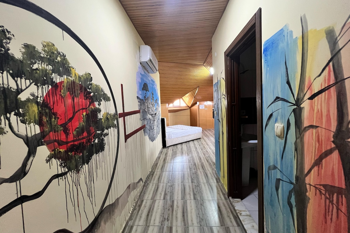 A hallway with a bed, a wooden ceiling, and a wall with a large abstract painting.