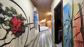 Un pasillo con una cama, techo de madera y una pared decorada con un cuadro abstracto grande.