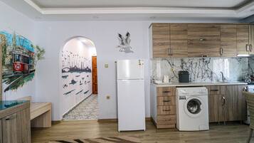 Una cocina moderna con armarios de madera, un refrigerador blanco, una lavadora y un protector de salpicaduras de azulejos.