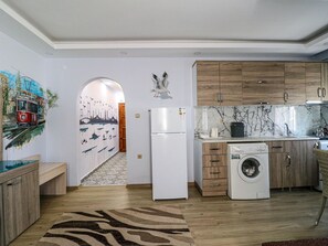 A modern kitchen with wooden cabinets, a white refrigerator, a washing machine, and a tiled backsplash.
