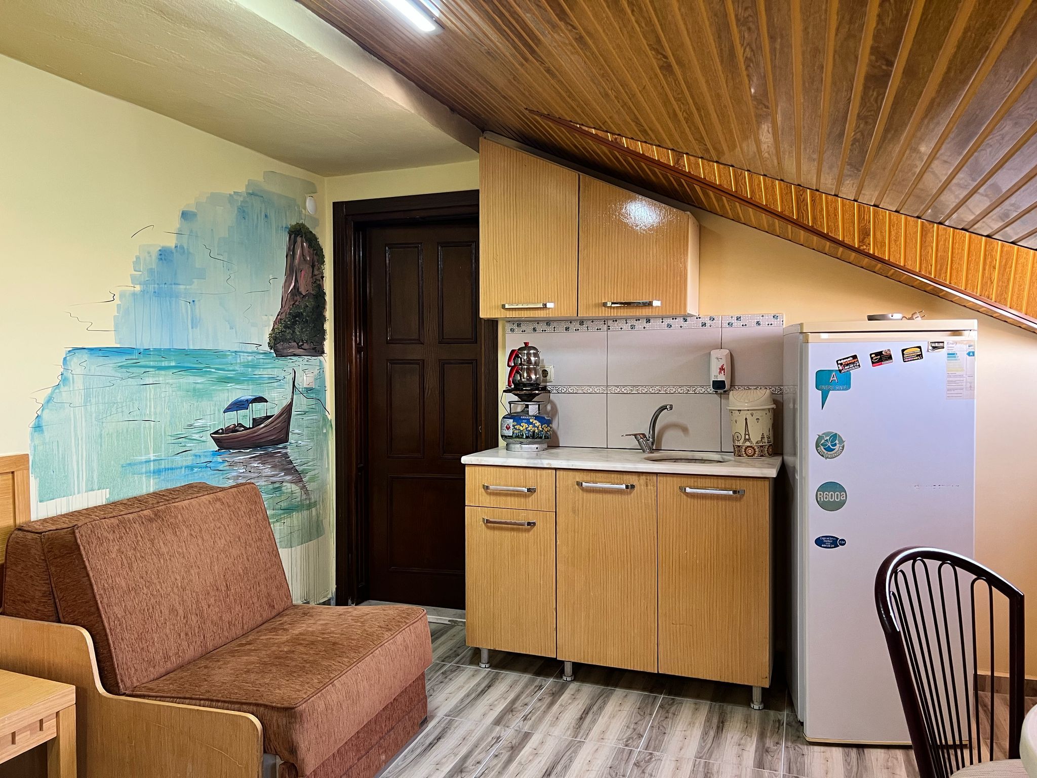 Una cocina compacta con armarios de madera, un refrigerador y un lavamanos.