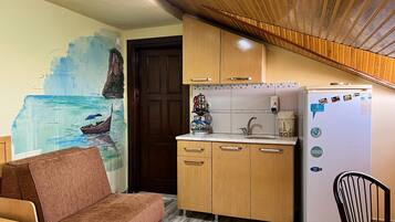 A compact kitchen with wooden cabinets, a refrigerator, and a sink.