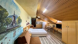 A compact room with a bed, a small desk, a chair, a mural, and a kitchenette. - Esma Apart Hotel (Alanya)