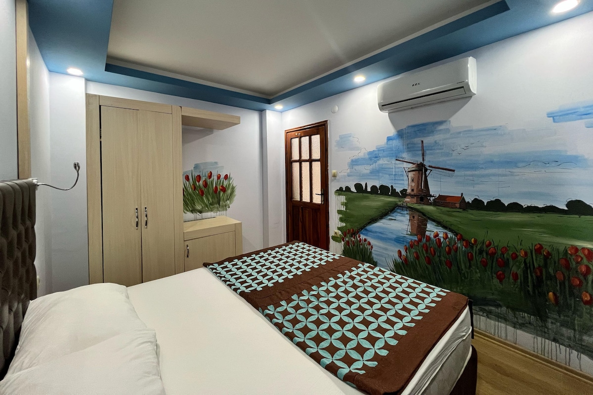 A bedroom with a bed, a wardrobe, a door, and a wall mural.