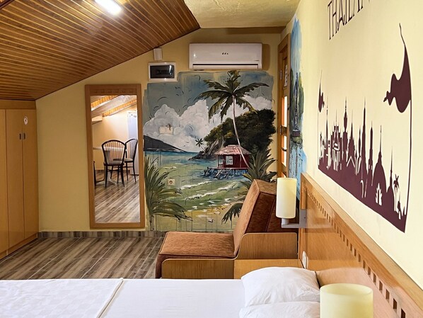 A hotel room with a bed, wooden furniture, a mural of a tropical beach scene, and a city skyline silhouette on the wall. - Esma Apart Hotel (Alanya)