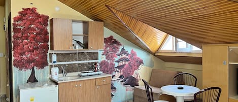 A compact kitchen with wooden cabinets, a sink, and a dining area with chairs.