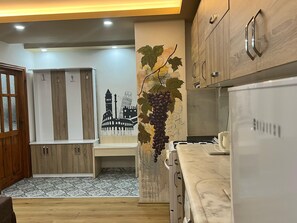 A modern kitchen with wooden cabinets, a marble countertop, and a wall-mounted sink. - Esma Apart Hotel (Alanya)
