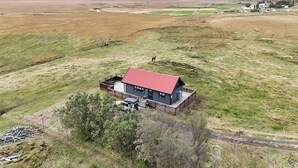 A single-story house with a red roof, surrounded by a fenced yard and a small garden. - Áshamrar - cottage 1 (Ásahreppur)