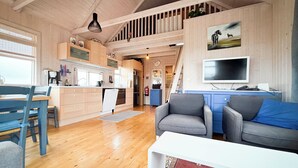 A spacious living area with a dining table, a sofa, and a TV. - Áshamrar - cottage 1 (Ásahreppur)