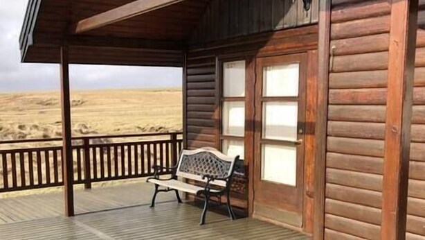 A wooden cabin with a porch, a bench, and a view of the desert. - Áshamrar - cottage 1 (Ásahreppur)