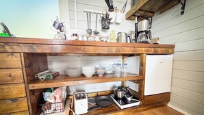 Una cocina con armarios de madera, un refrigerador blanco y diversos utensilios y electrodomésticos.