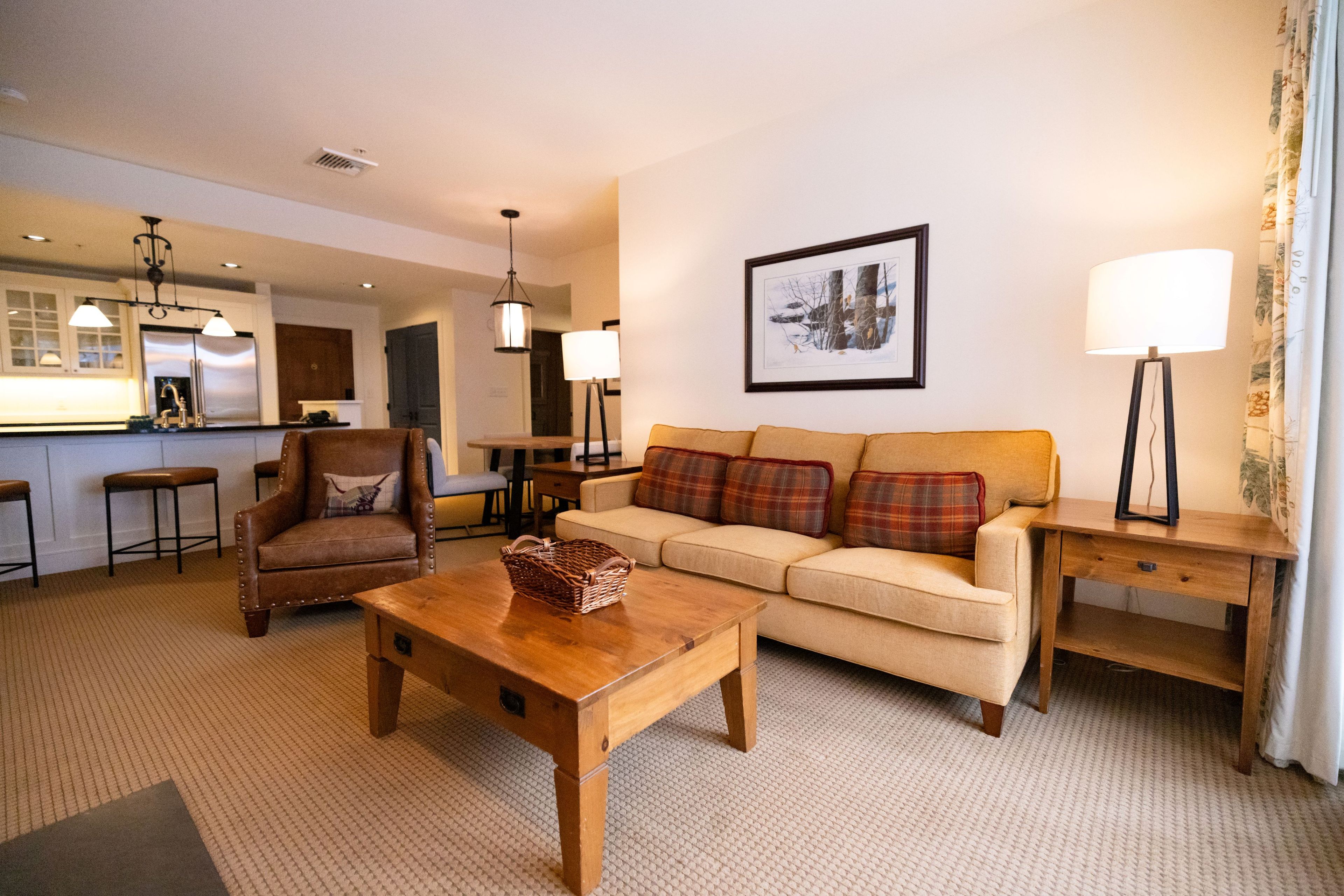A living room with a sofa, armchair, wooden coffee table, and a lamp.