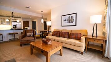 A living room with a sofa, armchair, wooden coffee table, and a lamp.