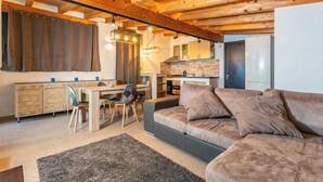A modern kitchen with wooden beams, a dining area with a table and chairs, and a living room with a sofa. - Vanilla Bay Dep Apartment with Private Pool, Private Garden, and Air Conditioning (San Giovanni La Punta)