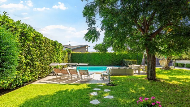 A backyard with a swimming pool, a patio with chairs, and a hedge. - Vanilla Bay Dep Apartment with Private Pool, Private Garden, and Air Conditioning (San Giovanni La Punta)