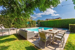Un jardin avec une piscine, du mobilier d’extérieur et une pelouse bien entretenue.