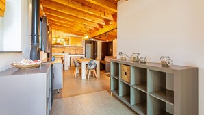 A modern kitchen with wooden beams, a dining area, and a built-in shelving unit. - Vanilla Bay Dep Apartment with Private Pool, Private Garden, and Air Conditioning (San Giovanni La Punta)